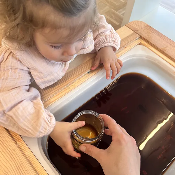 Enfants observant des insectes en plastique avec une loupe improvisée dans la crèche 6 Sens à Saint-Sulpice.