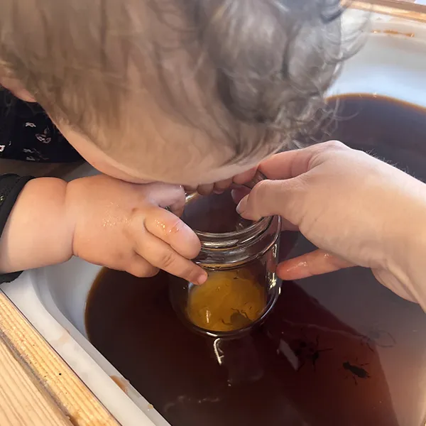 Enfants observant des insectes en plastique avec une loupe improvisée dans la crèche 6 Sens à Saint-Sulpice.