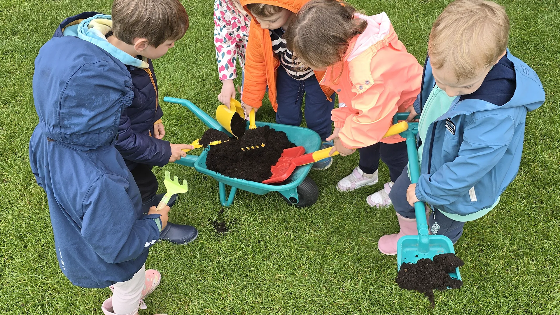Enfants semant des graines de gaillardes encadrés par une éducatrice